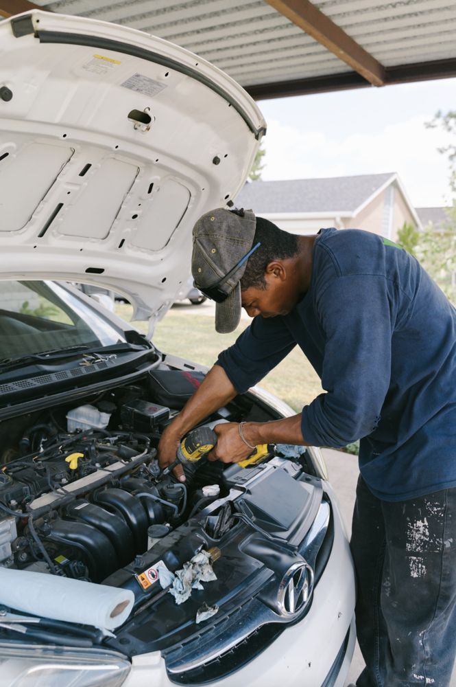 Tulsa mobile mechanic at work under a hood in a driveway